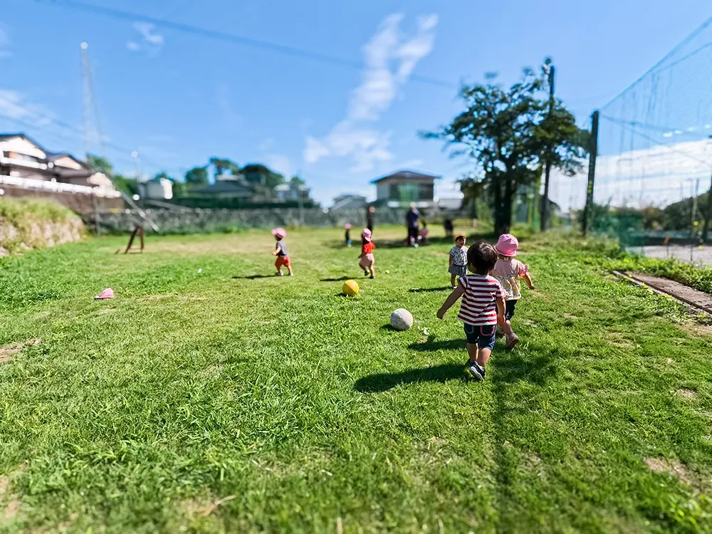 芝生広場で裸足で走り回る子どもたちの様子